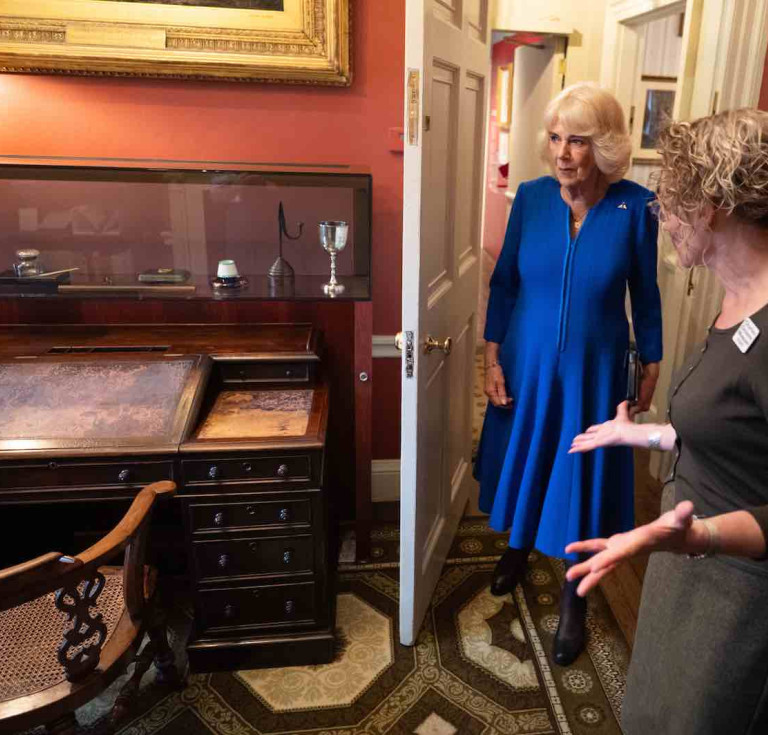 Her Majesty The Queen takes a look at Dicken's desk